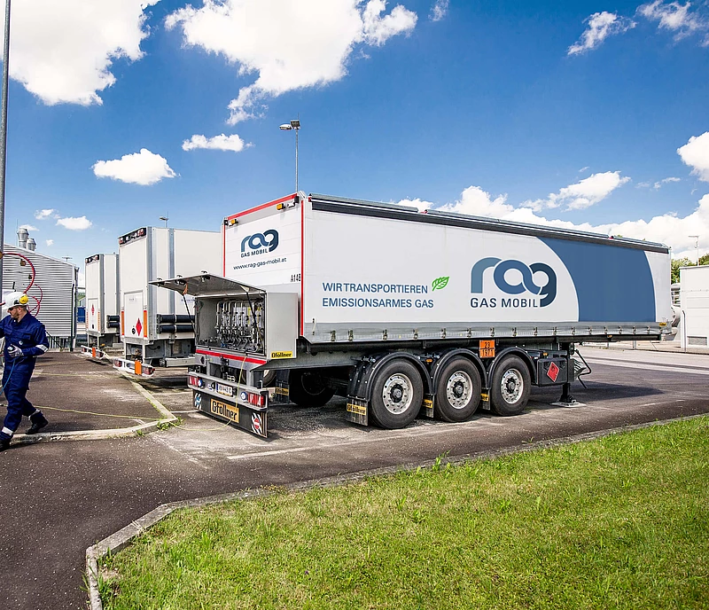 CNG trailer with RAG branding in parking lot behind green field