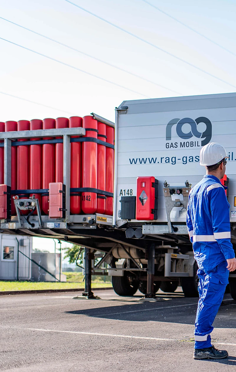 RAG Mitarbeiter in Schutzkleidung vor zwei LKWs mit RAG Branding von hinten