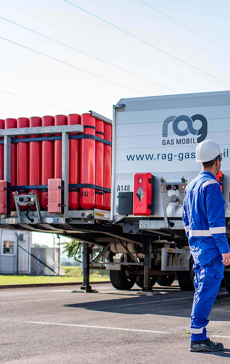 RAG Mitarbeiter in Schutzkleidung vor zwei LKWs mit RAG Branding von hinten