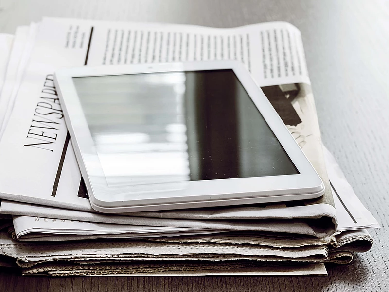 Tablet lying on a stack of newspapers